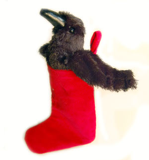 A little plush crow is sitting inside a red Santa stocking