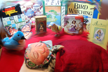 A little old lady wearing a headscarf sleeps while images of toys and games are around her, bird game, word game, bluebird plush, and others.
