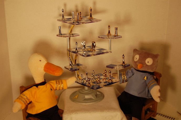 A plush duck dressed as Captain Kirk and a Plush owl dressed as Spock play Three-dimensional chess